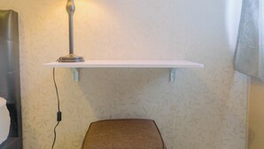 A room with a white wall, a hanging lamp, a white shelf, and a brown chair. - New Furnished Studio Apartment at Gunung Putri Square (Gunung Putri)