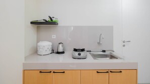 A kitchen with a countertop, a sink, a kettle, a coffee maker, and a toaster. - City View 2BR Bogorienze Apartment near The Jungle Fest (Bogor)