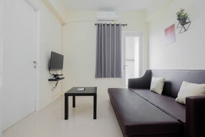Relax in this cozy space with a sofa, flat-screen TV, and air conditioning unit.