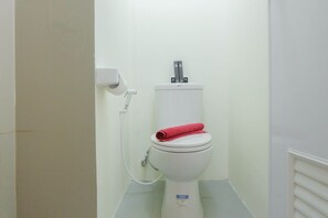 A compact bathroom with a white toilet and a bathtub, featuring a light grey tile floor.