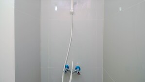 A shower with a handheld showerhead and two faucets. - Cozy Studio Bogorienze Resort Apartment (Bogor)