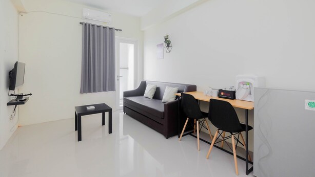 A modern living room with a sofa, a small table, a TV, and a desk with a chair. - Cozy 2BR Bogorienze Resort Apartment near Nirwana Residence (Bogor)