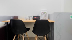 A small office space with a desk, two black chairs, a coffee machine, and a refrigerator. - Cozy 2BR Bogorienze Resort Apartment near Nirwana Residence (Bogor)