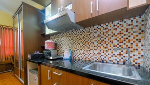 A kitchen with wooden cabinets, a stainless steel sink, and a tiled backsplash. - Comfortable Studio Apartment at Taman Melati near Universitas Indonesia (Depok)