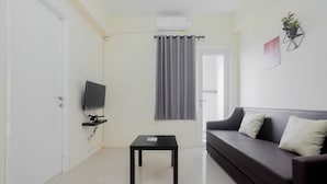 A modern living room with a dark sofa, a small black table, a mounted TV, and a grey curtain.