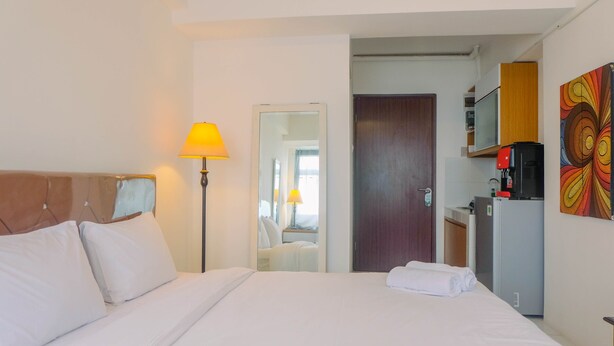 Una habitación de hotel con una cama, una lámpara, una puerta, un microondas y un refrigerador.