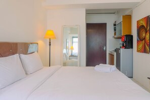 Ein Hotelzimmer mit Bett, Lampe, Tür, Mikrowelle und Kühlschrank.