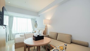 A modern hotel room with a bed, a sofa, a round table, and a lamp. - Modern and Spacious Studio Grand Kamala Lagoon Apartment (Bekasi)