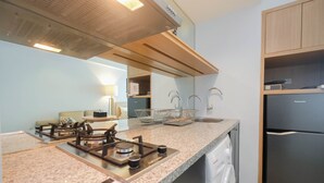 A modern kitchen with a gas stove, built-in dishwasher, and a stainless steel refrigerator. - Modern and Spacious Studio Grand Kamala Lagoon Apartment (Bekasi)