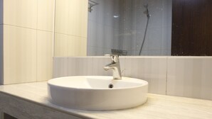 A bathroom with a white sink, a mirror, and a shower area. - Compact Studio Room @ Galeri Ciumbuleuit 2 Apartment (Bandung)