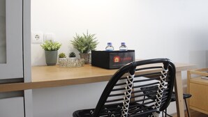 A wooden desk with a black chair, a box of bottled water, and small potted plants. - Comfy & Artsy Studio at Beverly Dago Apartment (Bandung)