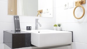 A modern bathroom with a white sink, black countertop, and a wooden toilet paper holder. - Comfy & Artsy Studio at Beverly Dago Apartment (Bandung)