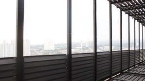 A high-rise building with a view of a cityscape through large windows. - Comfy & Artsy Studio at Beverly Dago Apartment (Bandung)