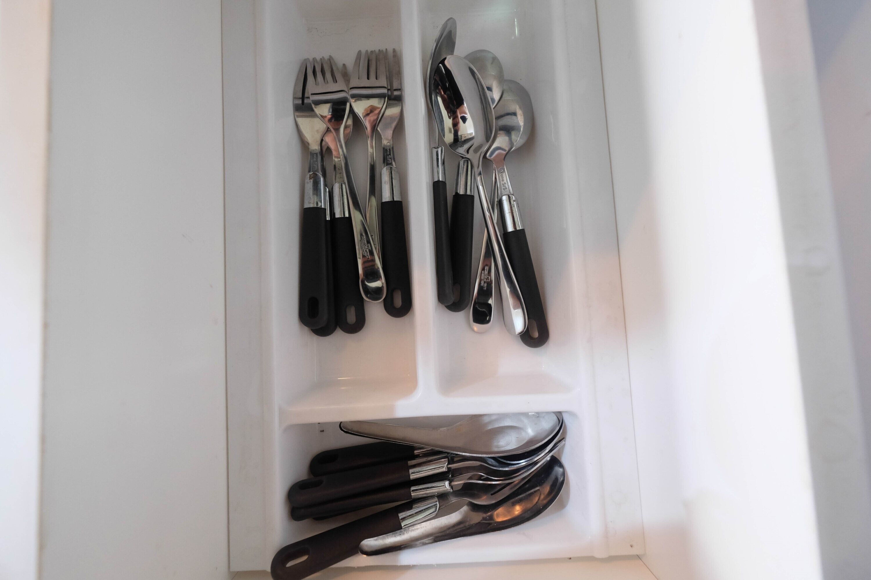 A drawer with neatly organized cutlery including forks, spoons, and knives.