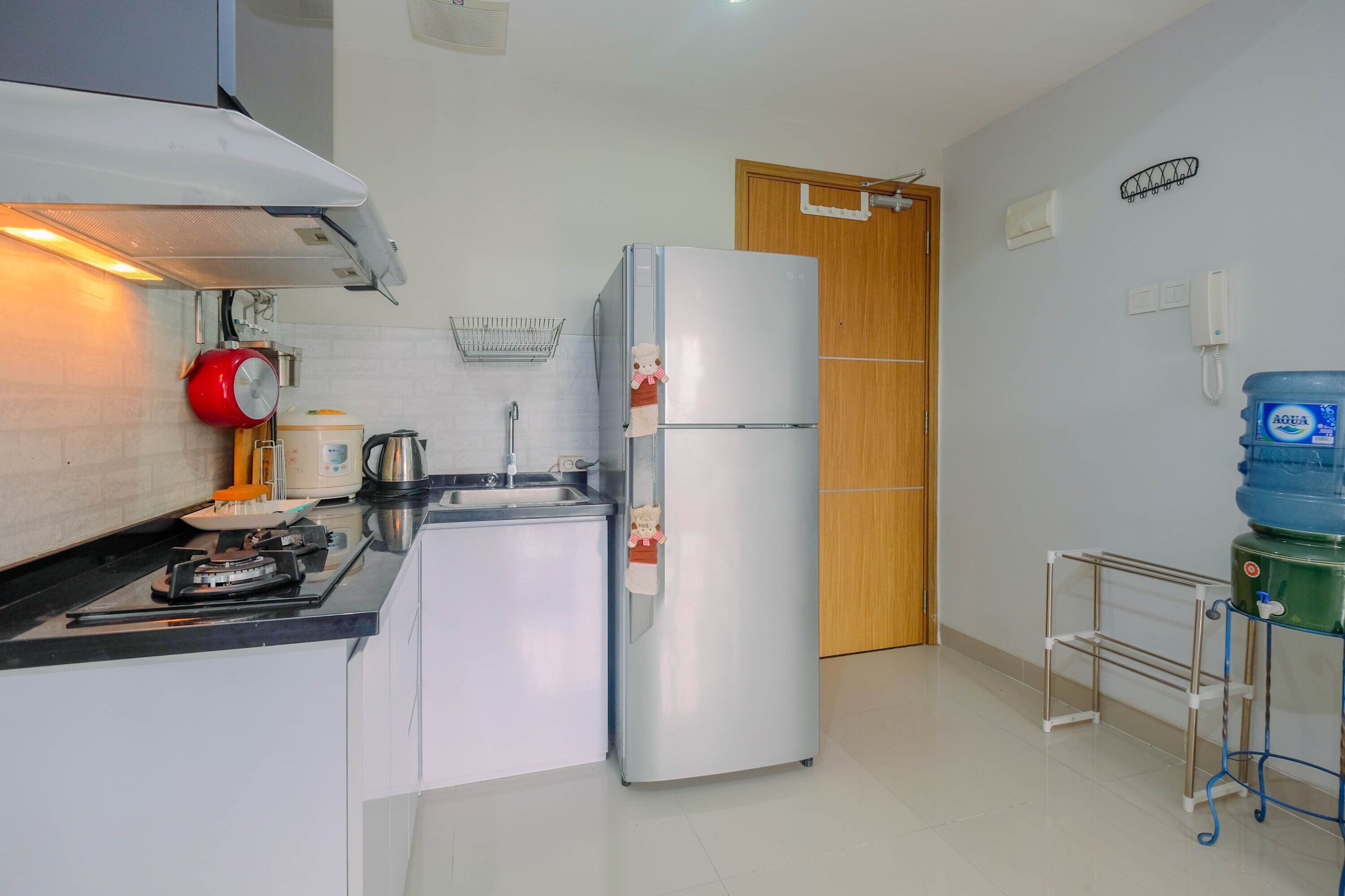 Cocina compacta con refrigerador, estufa, lavamanos y dispensador de agua.