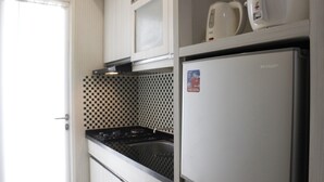 Una cucina compatta con microonde, bollitore e frigorifero Sharp.