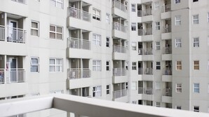 Un edificio residenziale a più piani con balconi, finestre e un corrimano in primo piano.