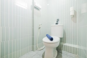 Une salle de bain équipée de toilettes, d’un bidet et d’un distributeur de serviettes.