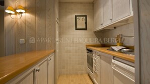 Una cocina compacta con armarios de madera, horno empotrado y lavavajillas.