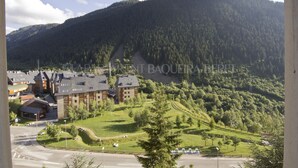 Un hotel con varias construcciones, una zona de estacionamiento y montañas al fondo.