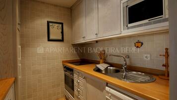 Una cocina con encimera de madera, pileta de acero inoxidable y salpicadero con azulejos blancos.