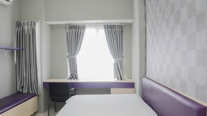 A hotel room with a bed, a desk with a chair, and a window with curtains. - Comfortable 2BR Apartment at Taman Melati Margonda (Depok)
