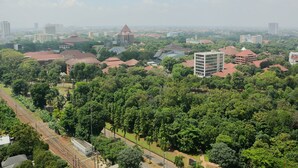 A cityscape with a mix of residential and commercial buildings, including a prominent tower and several smaller structures. - Comfortable 2BR Apartment at Taman Melati Margonda (Depok)