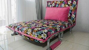 A bed with a floral bedspread and pink pillows, metal frame, and a white curtain in the background. - Comfortable 2BR Apartment at Taman Melati Margonda (Depok)