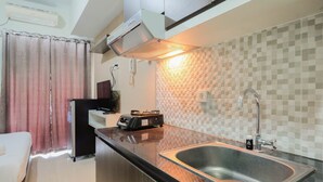 A compact kitchen with a sink, a microwave, and a toaster. - Simply Furnished Studio @ Grand Dhika City Apartment (Bekasi)