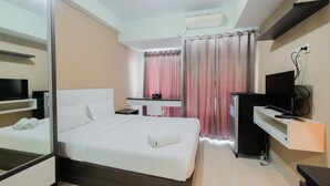 A hotel room with a bed, a desk, a TV, and a wardrobe. - Simply Furnished Studio @ Grand Dhika City Apartment (Bekasi)