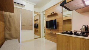 A compact kitchenette with a flat-screen TV, a coffee maker, and a microwave. - Modern Studio Apartment 27th on Top of Green Pramuka Mall (Jakarta)