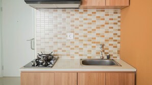 Een keuken met een gasfornuis, spoelbak en houten kastjes.
