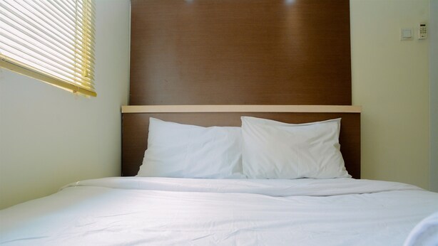 Een netjes opgemaakt bed met witte lakens en een houten hoofdbord.
