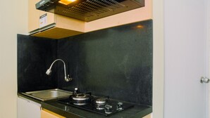 Een kleine keuken met een zwart aanrecht, een roestvrijstalen spoelbak en een gasfornuis.