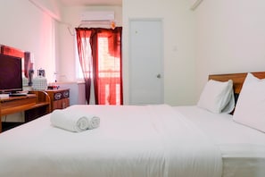 Relax in comfort with a neatly made bed, flat-screen TV, and workspace.