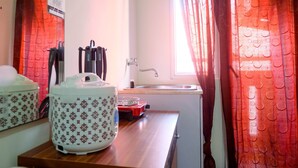 A kitchen with a sink, a stove, and two patterned containers on the counter. - Simply Studio Apartment at Green Pramuka City (Jakarta)