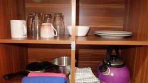 A wooden shelf with kitchenware, including a kettle, a frying pan, and a bowl. - Simply Studio Apartment at Green Pramuka City (Jakarta)