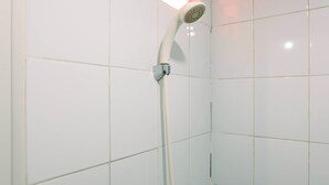 A shower with a white hose and head in a tiled bathroom. - Simply Studio Apartment at Green Pramuka City (Jakarta)