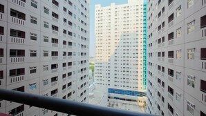A high-rise residential building with multiple balconies and a central courtyard. - 2BR Apartment Green Pramuka City near Shopping Mall (Jakarta)