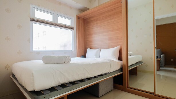 A modern bedroom with a bed, a window, and a wardrobe. - 2BR Apartment Green Pramuka City near Shopping Mall (Jakarta)
