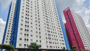 Um edifício alto com vários andares, apresentando uma combinação de fachadas brancas e azuis.
