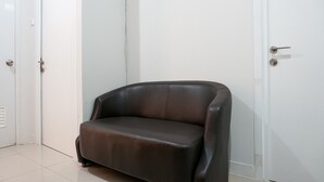 Um sofá de couro marrom escuro num quarto com paredes e porta brancas.