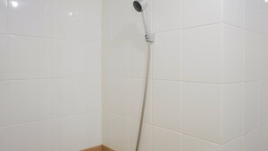 A shower with a handheld showerhead and a wall-mounted control. - Cozy Studio Green Pramuka Apartment next to Mall (Jakarta)