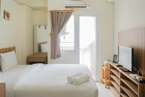 Ein Hotelzimmer mit Bett, Fernseher, Schreibtisch und einem Fenster mit Vorhängen.