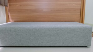 A room with a wooden headboard and a grey upholstered bench. - Connected to Mall 2BR Apartment at Green Pramuka City (Jakarta)