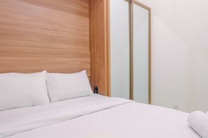 A neatly made bed with white linens in a modern room with wooden paneling and a sliding glass door closet.