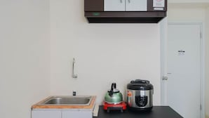 A compact kitchen with a sink, a kettle, and a rice cooker on the countertop.