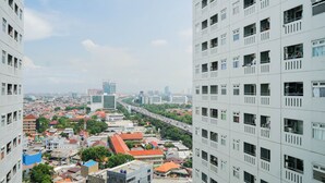 A high-rise building with multiple balconies and a view of a cityscape with various buildings and a highway.