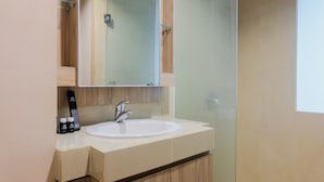 A modern bathroom with a white sink, a mirror, and a shower enclosure. - Studio Apartment with Mall Access at U Residence (Curug)