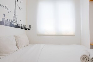 Une chambre d’hôtel avec un lit, du linge de lit blanc, une fenêtre avec des stores et un décor mural représentant des monuments emblématiques de Paris.